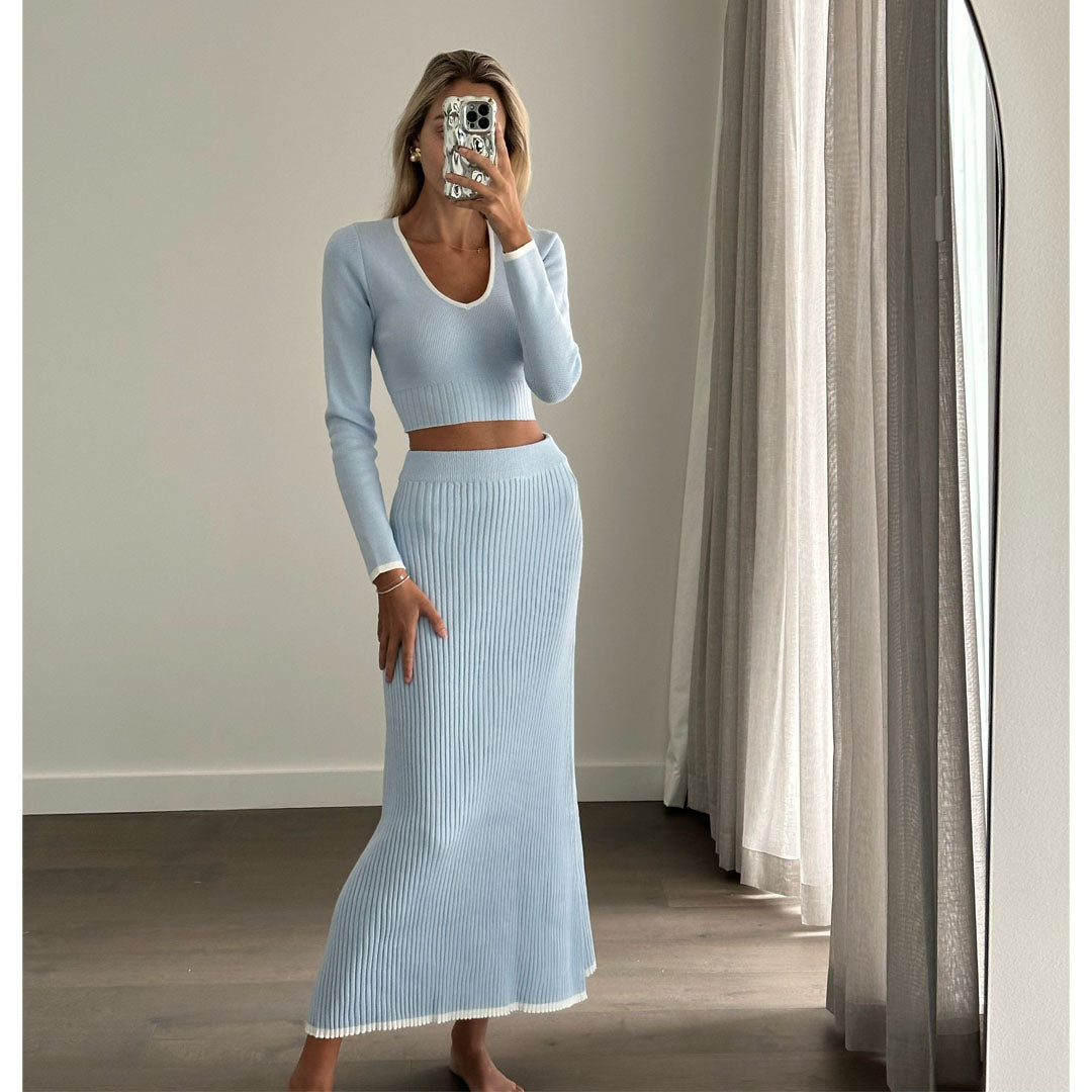 Female model online wearing baby blue long sleeve crop top with matching high waist baby blue knit pleated maxi skirt