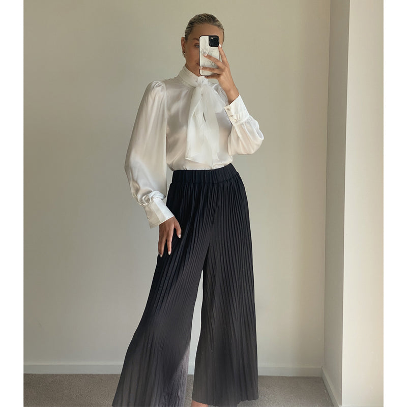 Female model wearing black high waist pleated pull on wide leg pants