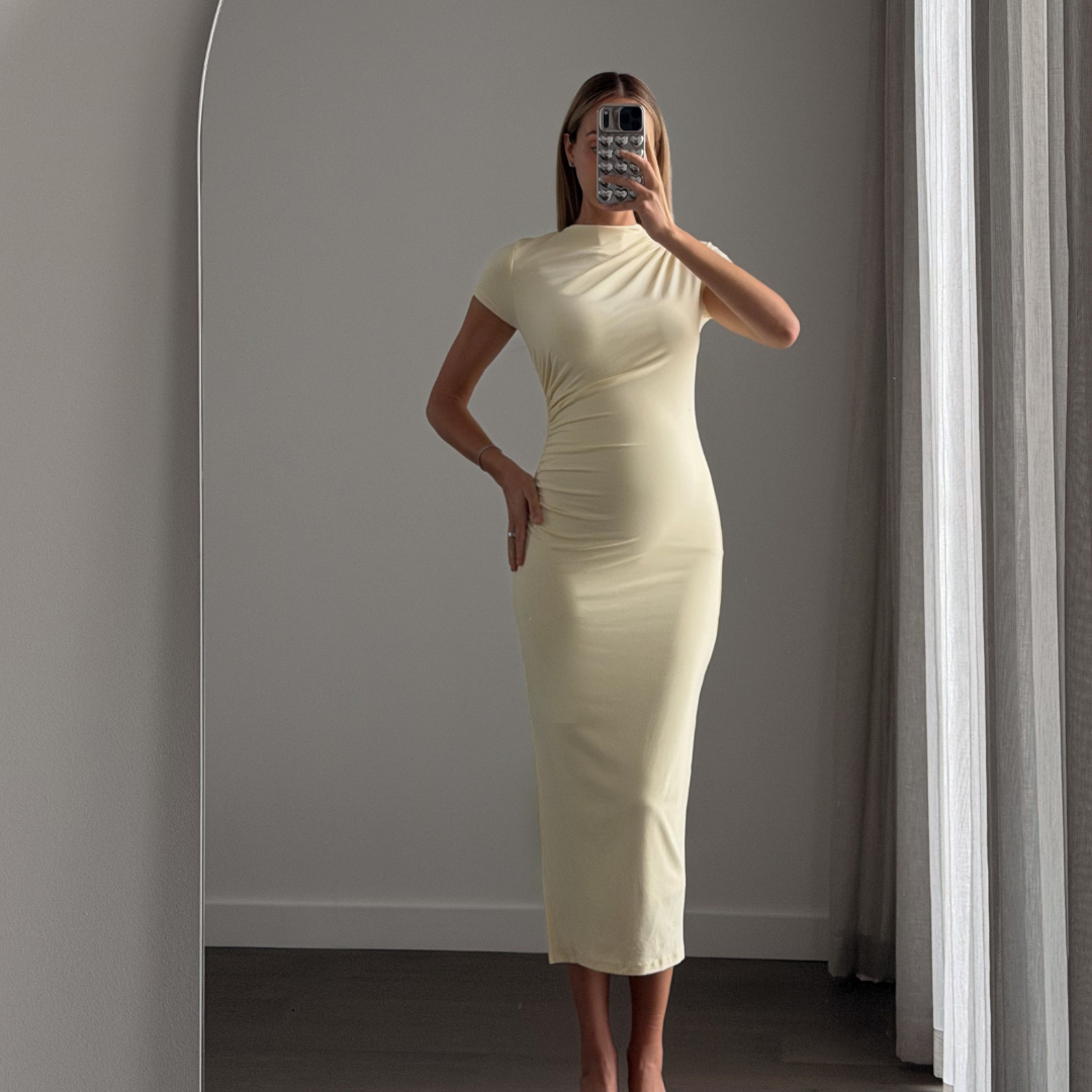 Matea BEYLA dress in baby yellow — fitted ruched midi with short sleeves, worn by a model six months pregnant, showing the dress's stretch and fit.