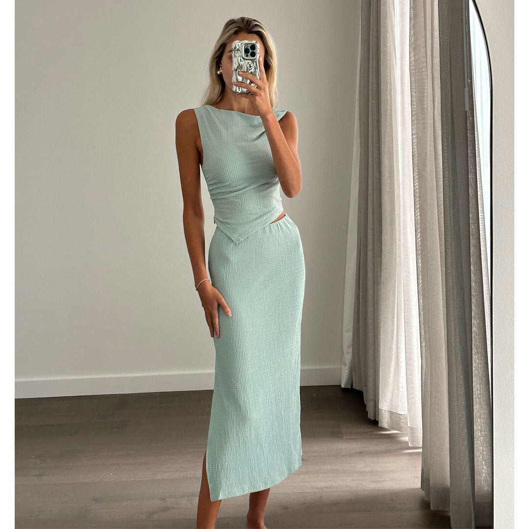 Female model online wearing teal tank crop top with high waisted teal textured midi skirt.
