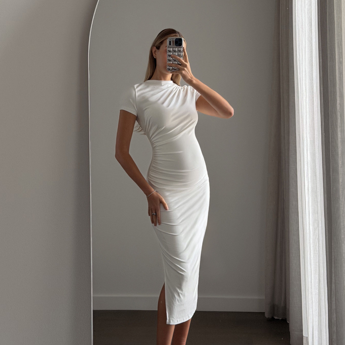 Woman wearing the Matea BEYLA baby yellow ruched midi dress showing side split, six months pregnant.