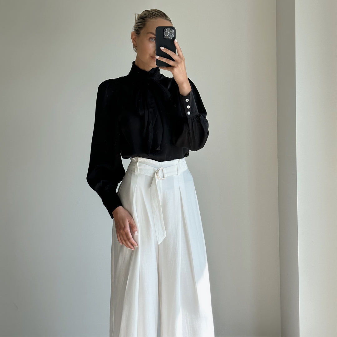 Female model wearing white pleated high waist wide leg pants