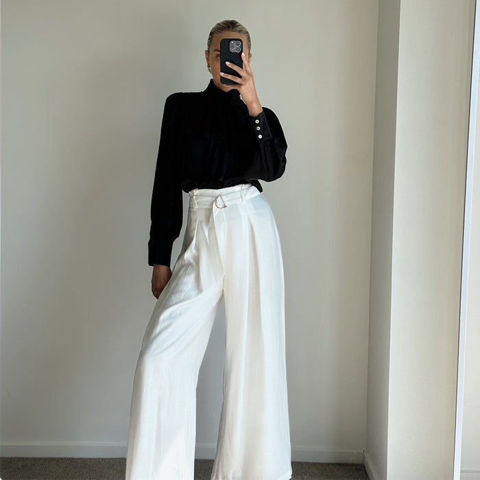 Female model wearing white pleated high waist wide leg pants
