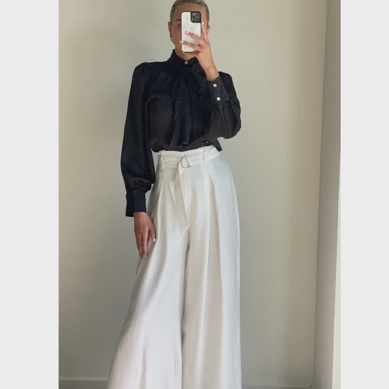 Female model wearing white pleated high waist wide leg pants