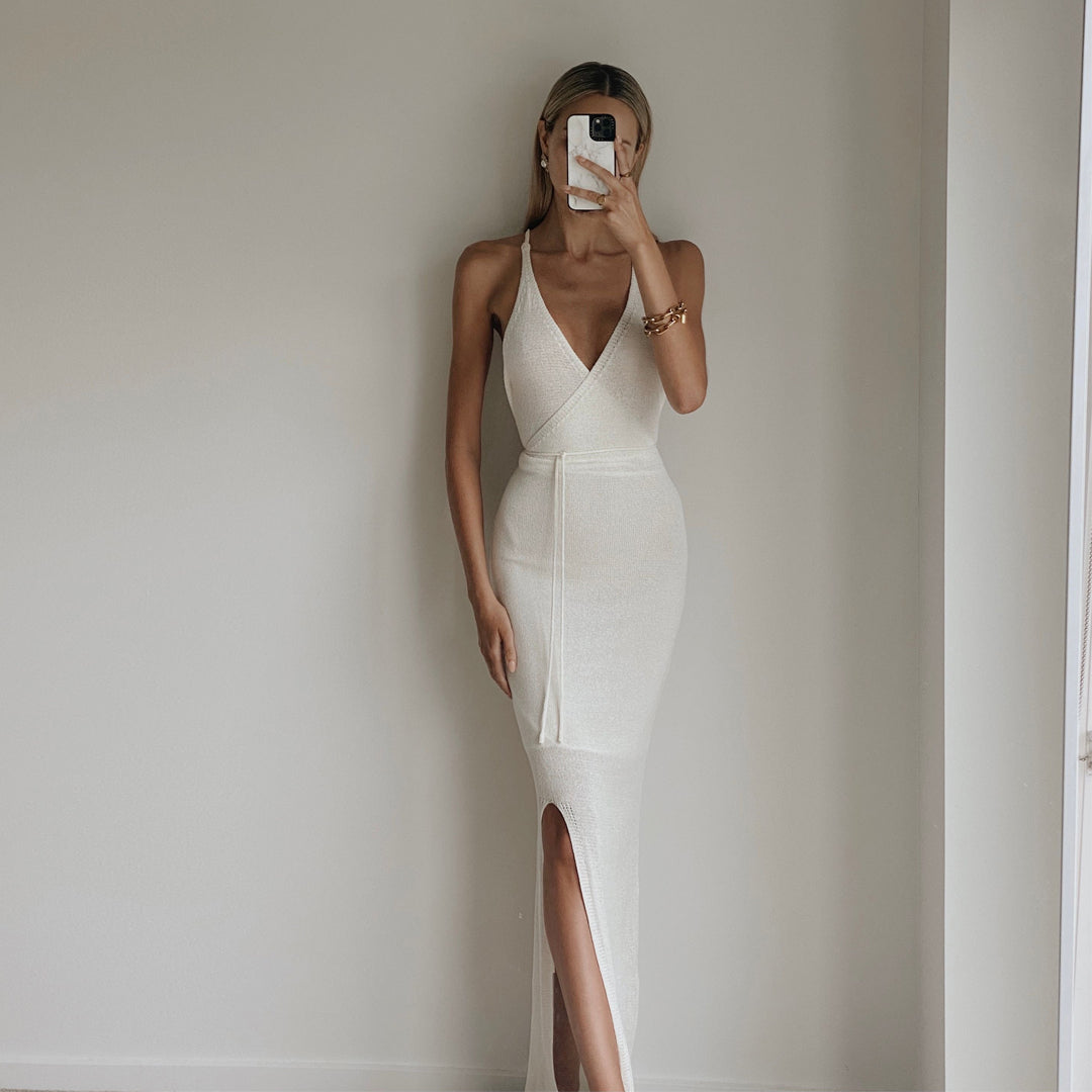 Female model online wearing ivory knit backless maxi dress with front split detail