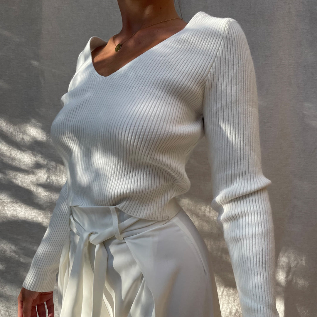 Female model wearing white long sleeve v neck knit top